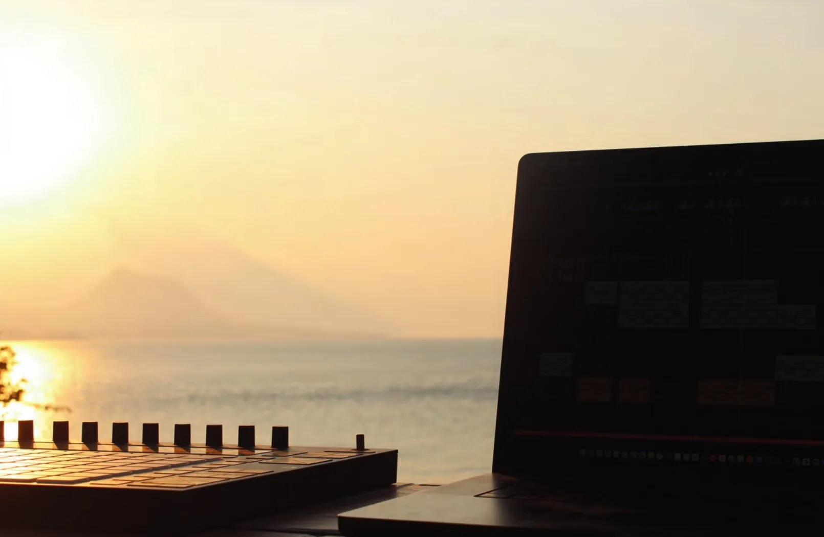 A controller and a laptop facing Lake Atitlán at sunset